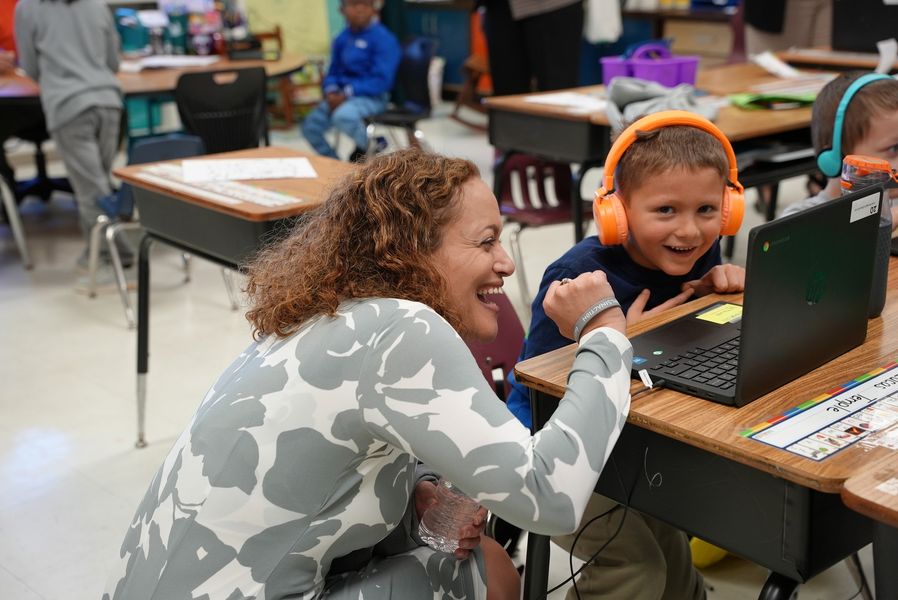 Teacher sitting beside student at desk